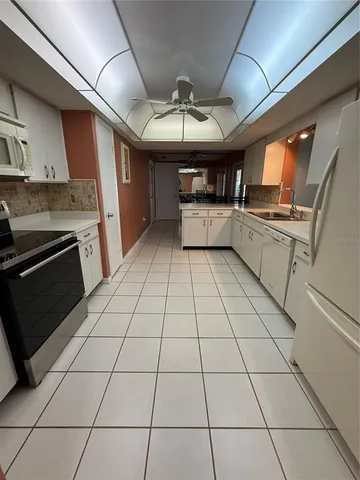 a kitchen with granite countertop a stove a sink and a refrigerator