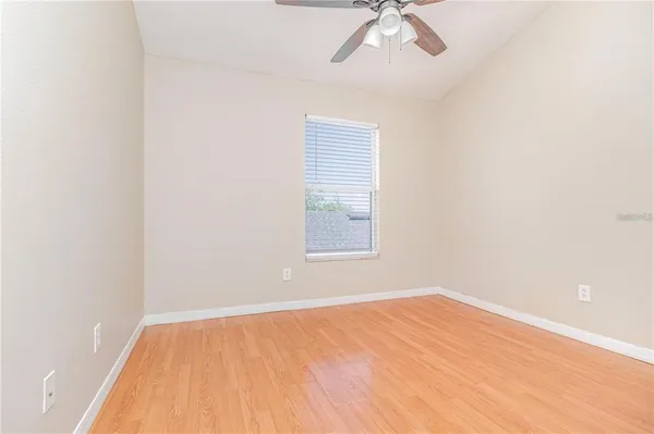 an empty room with a window and a ceiling fan