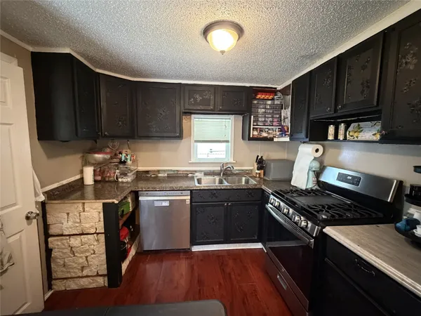 a kitchen with stainless steel appliances granite countertop a stove top oven a sink dishwasher and cabinets with wooden floor