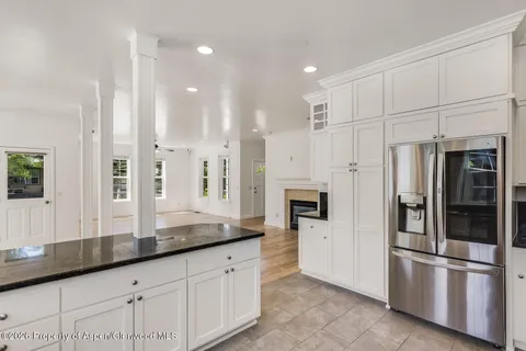 a kitchen with stainless steel appliances granite countertop a refrigerator a sink and white cabinets