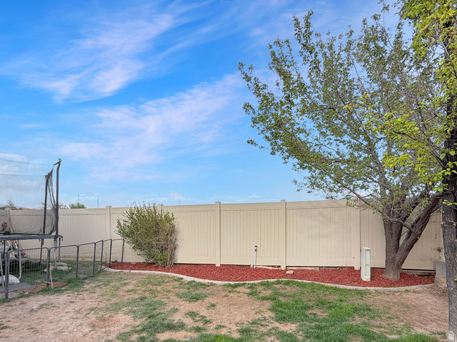 1716 Sagewood Road Price, UT 84501 - Photo 68 of 73 Expansive backyard featuring a full privacy fence, mature trees, landscaped planting beds with red mulch, and a combination of grass and natural ground cover