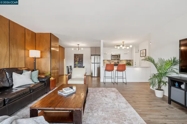 a living room with furniture a wooden floor and a kitchen view
