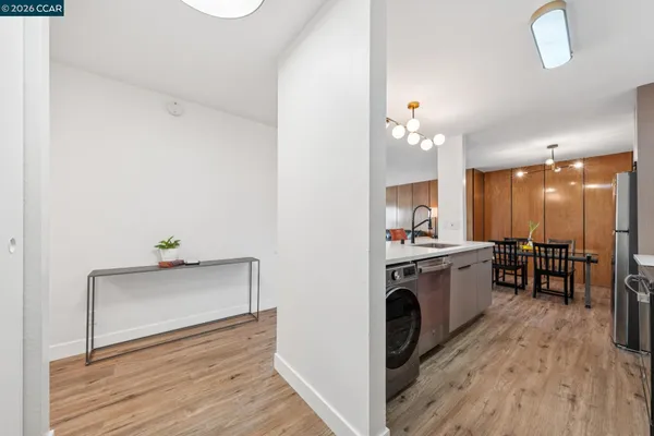 a view of living room kitchen with stainless steel appliances wooden floor large window and wooden floor
