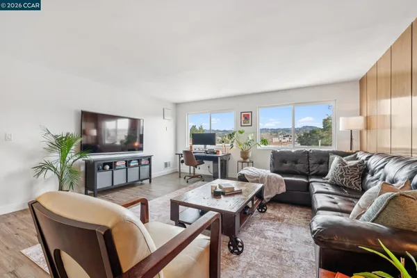 a living room with furniture kitchen view and a flat screen tv
