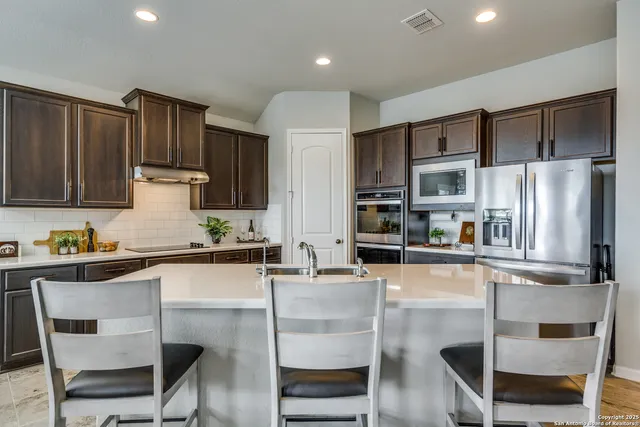 a kitchen with stainless steel appliances kitchen island granite countertop a refrigerator and a stove top oven