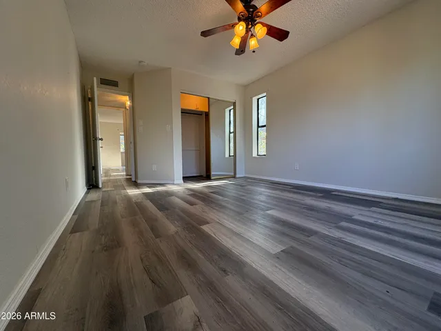 a view of an empty room with window and wooden floor