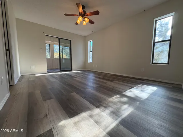a view of an empty room with window and wooden floor