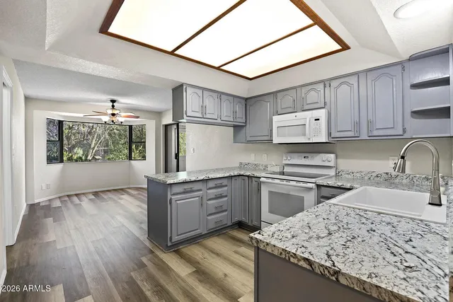 a kitchen with stainless steel appliances granite countertop a sink dishwasher stove and refrigerator with wooden floor