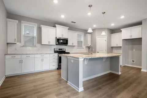 a kitchen with kitchen island granite countertop white cabinets and stainless steel appliances