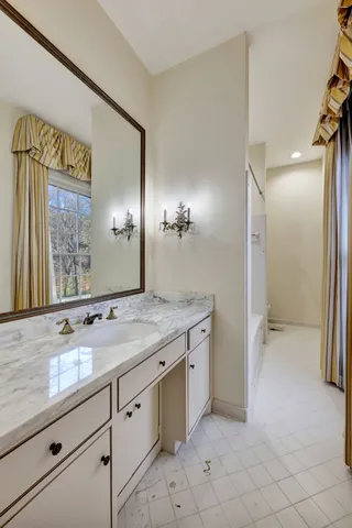 a spacious bathroom with a granite countertop sink and a mirror