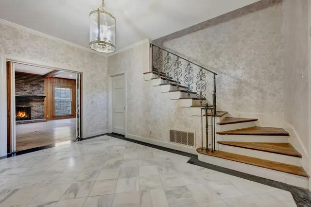 a view of an empty room with wooden floor fireplace and a window