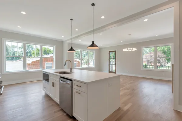 a kitchen with a sink stainless steel appliances and wooden floor