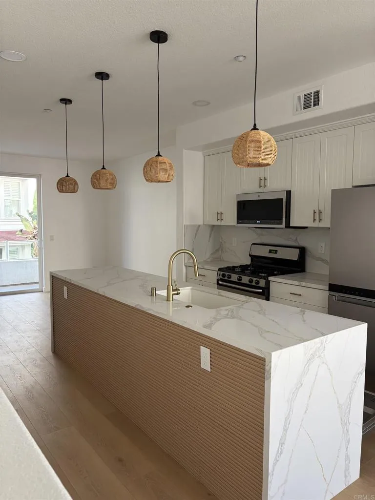 a kitchen with stainless steel appliances granite countertop a sink a stove and a wooden floor