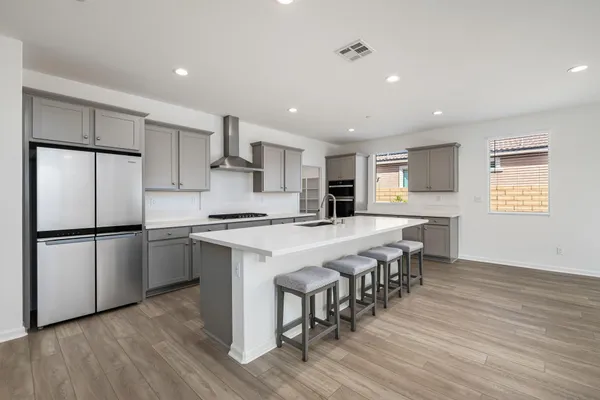 a large white kitchen with wooden floor and stainless steel appliances