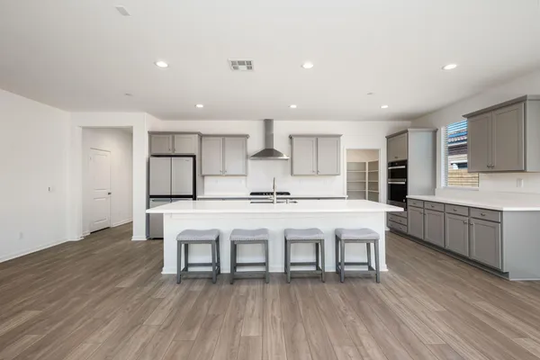 a kitchen with stainless steel appliances a dining table chairs stove refrigerator and cabinets