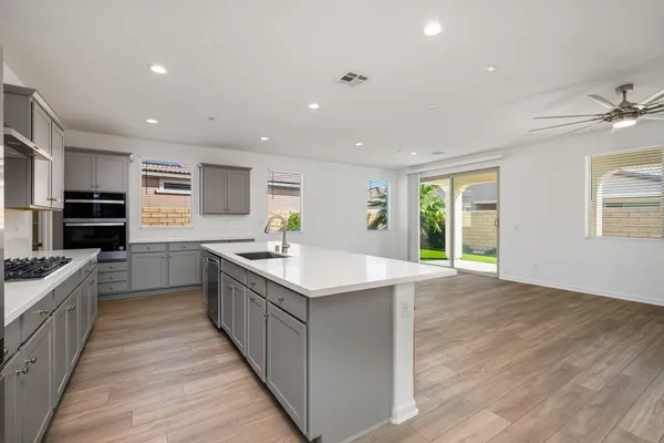 a large kitchen with cabinets wooden floor stainless steel appliances and dining table
