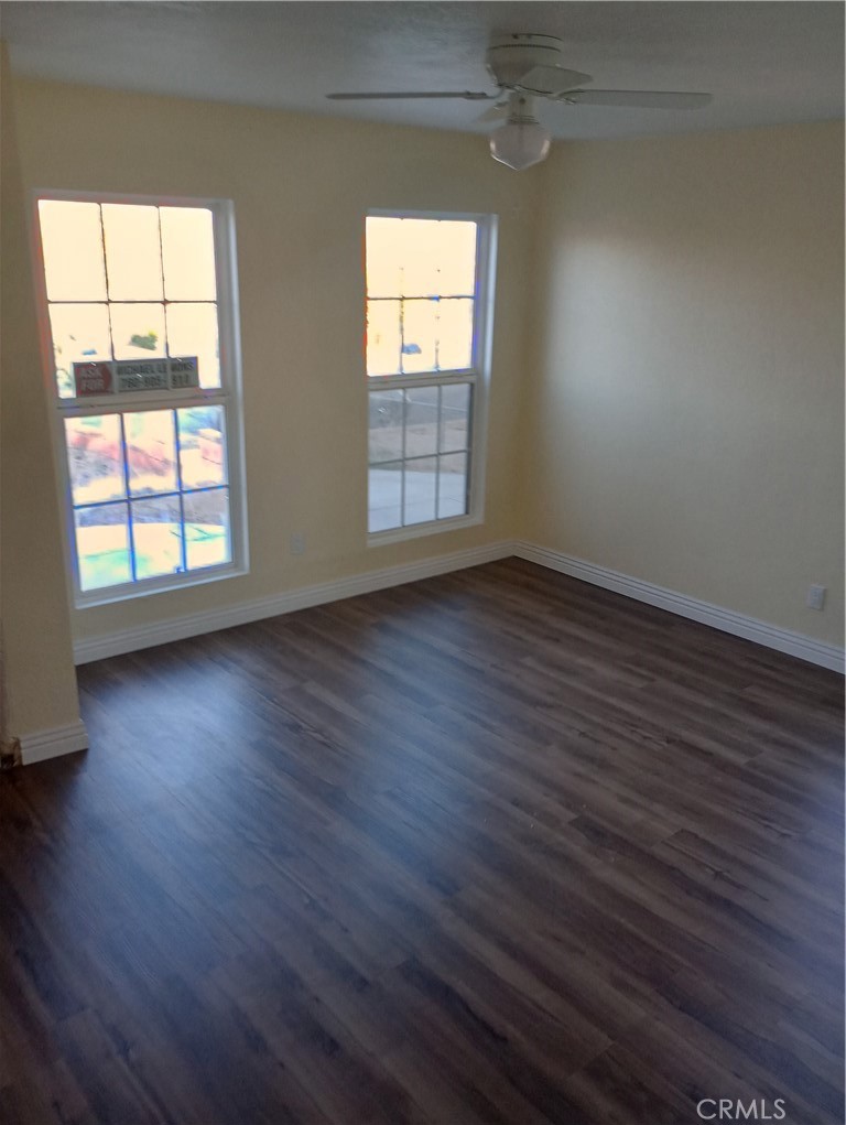 1426 Riverside Drive Barstow, CA 92311 - Photo 17 of 19 an empty room with wooden floor and windows