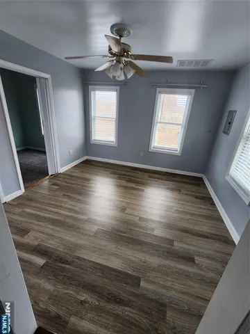 a view of empty room with wooden floor and fan