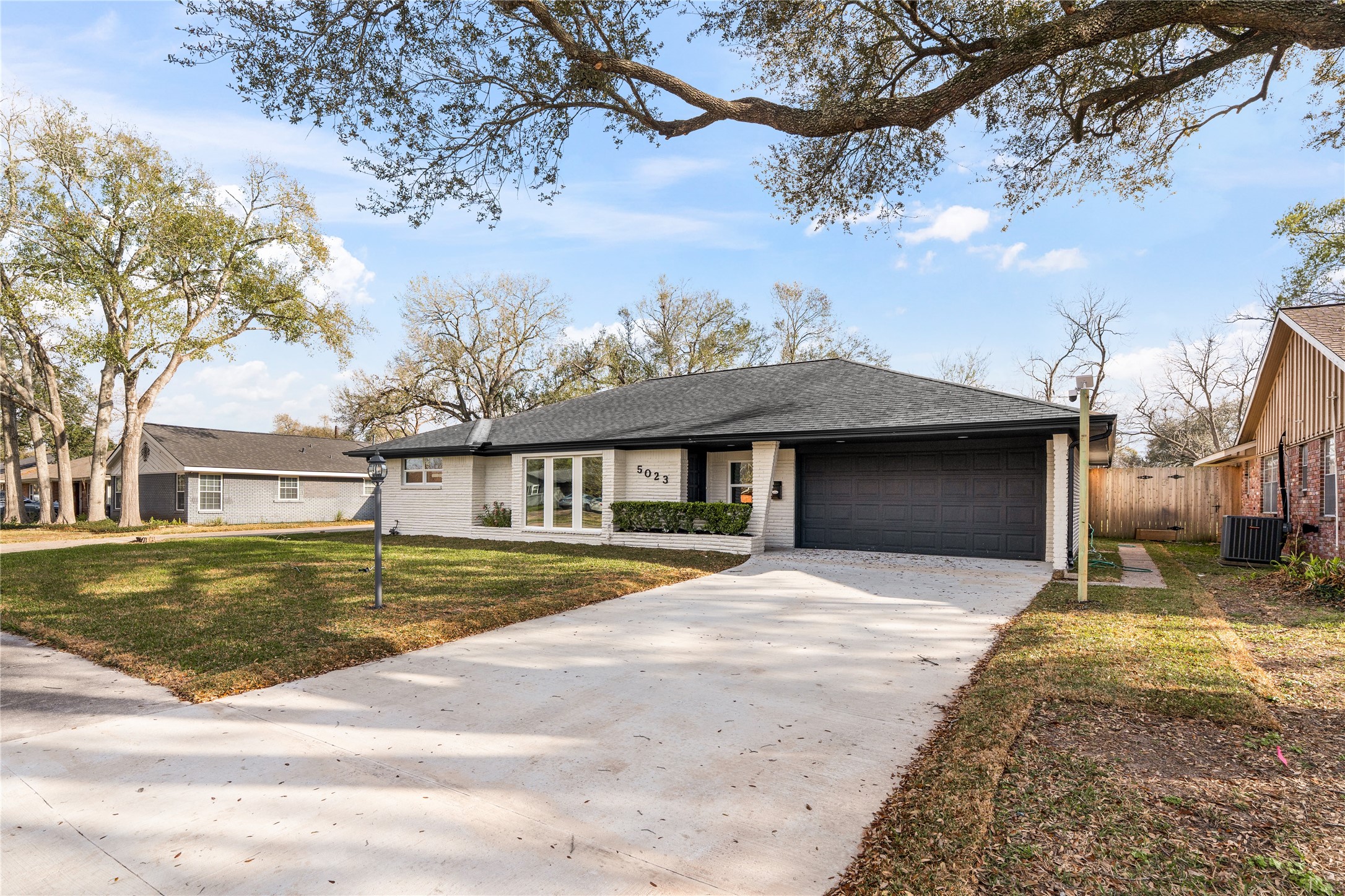 5023 Redstart Street Houston, TX 77035 - Photo 3 of 34 This stunning contemporary residence showcases a crisp, light-toned exterior accented by dual sleek black garage doors for a sophisticated modern aesthetic.