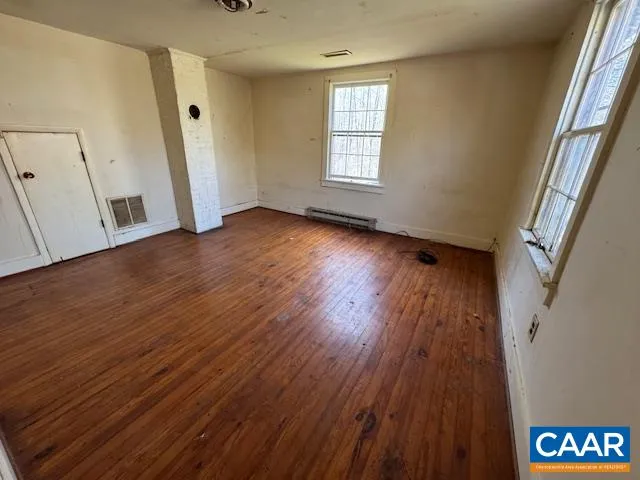 an empty room with wooden floor and windows