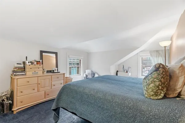 a bedroom with a bed and a lamp on dresser