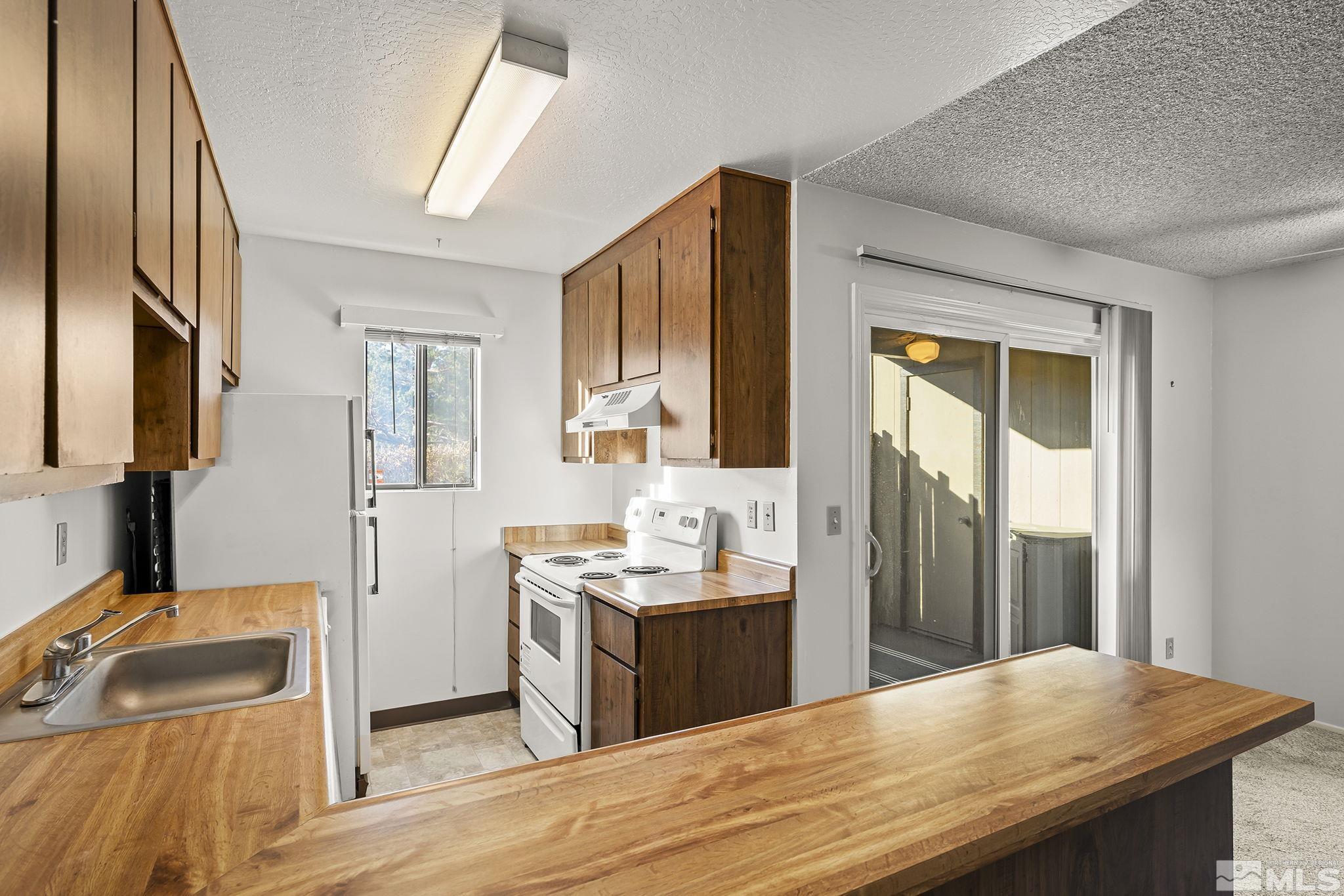 4893 Reggie Road Reno, NV 89502 - Photo 7 of 27 a kitchen with stainless steel appliances kitchen island granite countertop a sink stove and cabinets