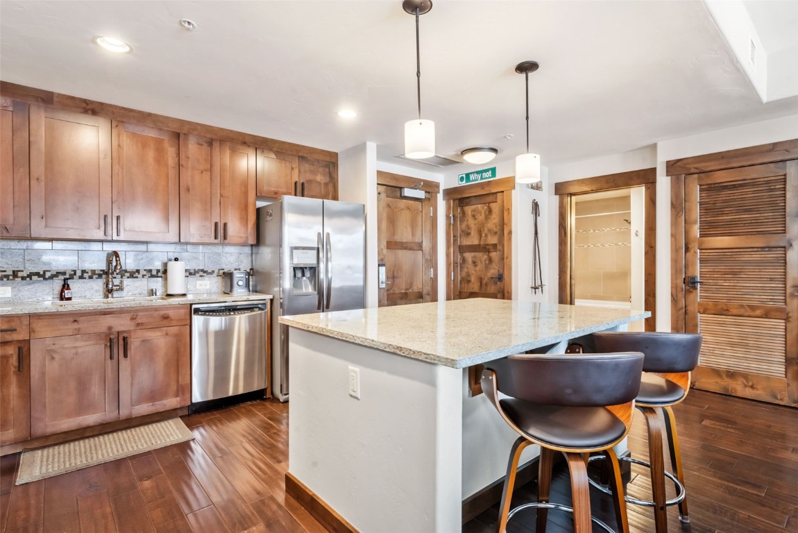 1175 Bangtail Way, Unit 4120 Steamboat Springs, CO 80487 - Photo 12 of 43 a open kitchen with stainless steel appliances granite countertop a stove a refrigerator a sink dishwasher a dining table and chairs with wooden floor