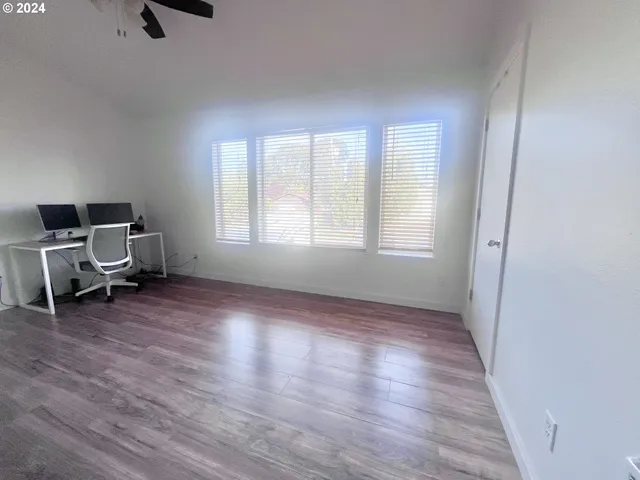an empty room with windows furniture and a ceiling fan