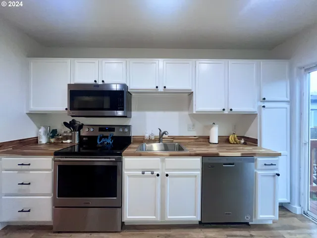 a kitchen with stainless steel appliances a sink dishwasher a stove and a microwave