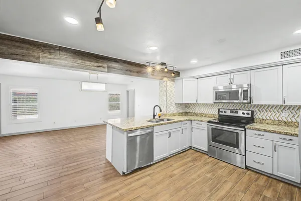 a kitchen with stainless steel appliances granite countertop a stove cabinets and wooden floor