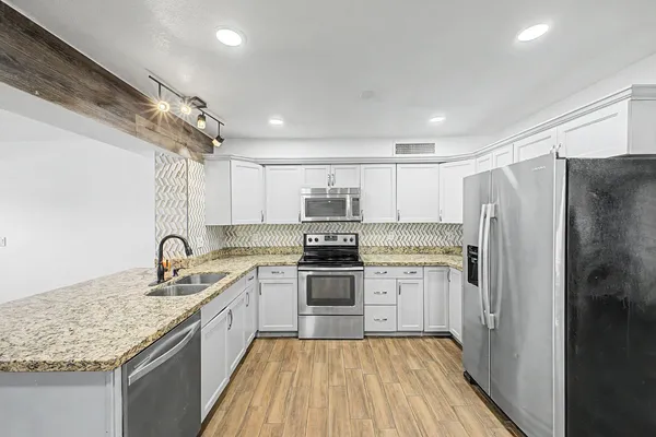 a kitchen with granite countertop stainless steel appliances cabinets a sink and a counter top space