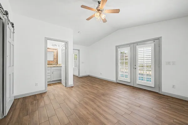 an empty room with wooden floor cabinet and windows
