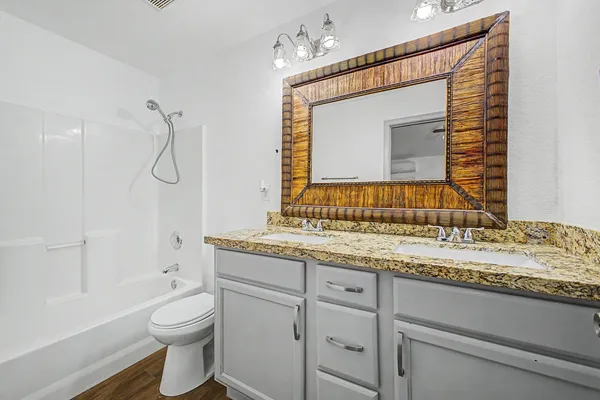 a bathroom with a granite countertop sink toilet and mirror