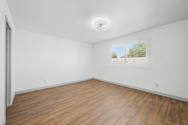 an empty room with wooden floor and windows