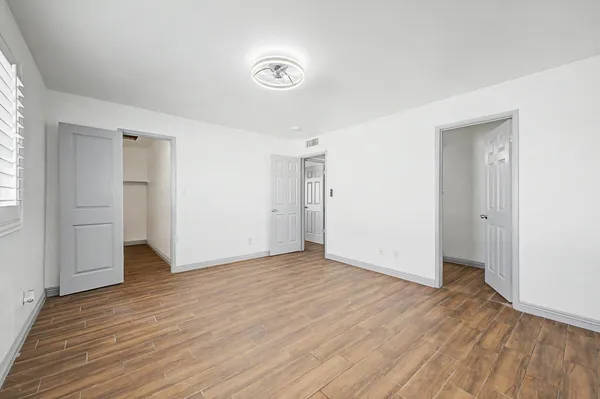 an empty room with wooden floor & windows