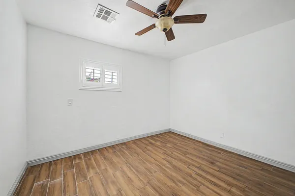 an empty room with a window and ceiling fan