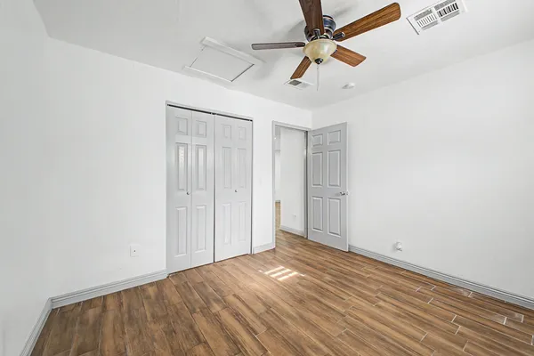 an empty room with wooden floor ceiling fan and window