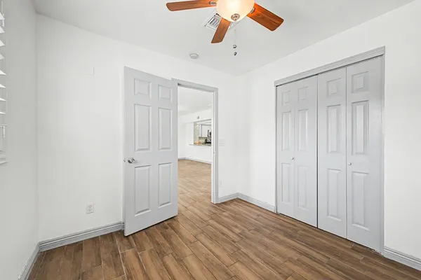an empty room with wooden floor cabinet and a ceiling fan