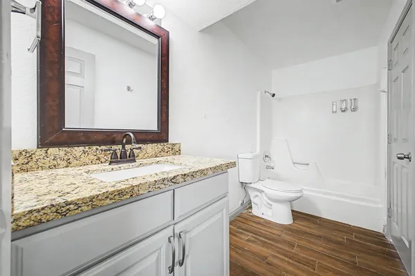 a bathroom with a granite countertop toilet sink and mirror