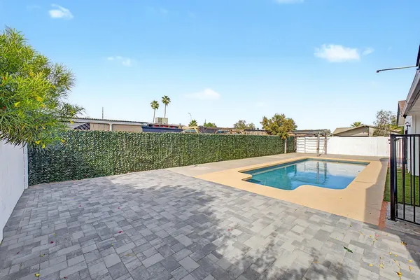 a view of a swimming pool with a chair and tables in the background