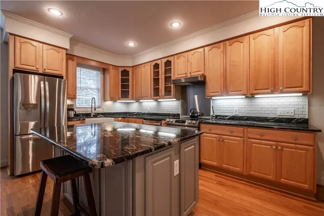 a kitchen with stainless steel appliances granite countertop a sink a stove and a refrigerator