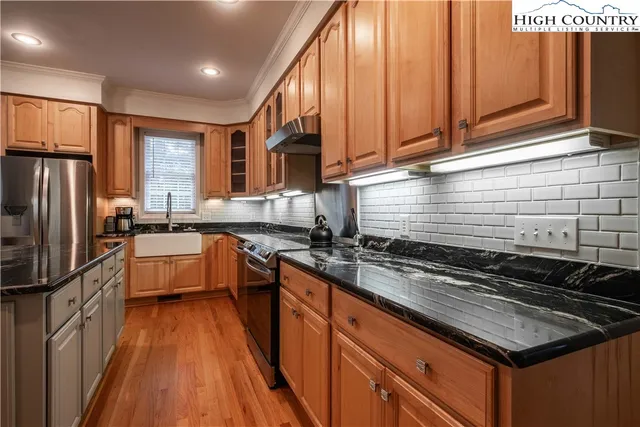 a kitchen with granite countertop a sink a counter space stainless steel appliances and cabinets