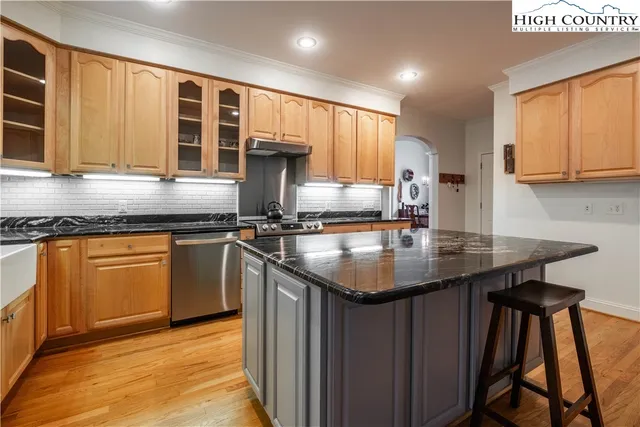 a kitchen with stainless steel appliances granite countertop a sink a stove window and cabinets
