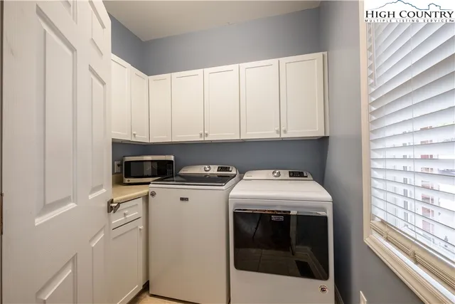 a utility room with stainless steel appliances a stove a sink and a microwave