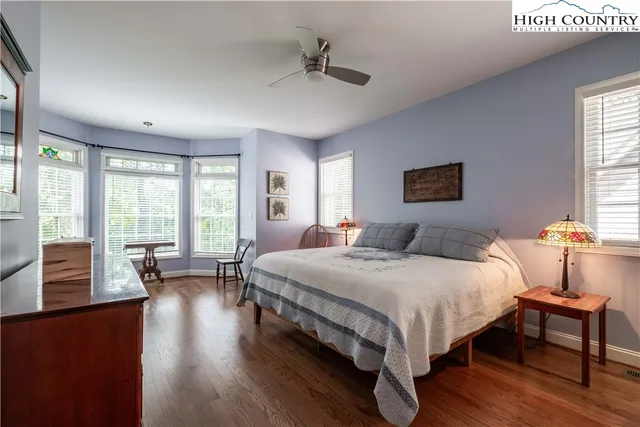 a bedroom with a bed a couch and large windows