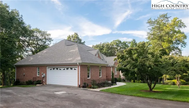 a view of a house with a yard and table and chairs under an umbrella