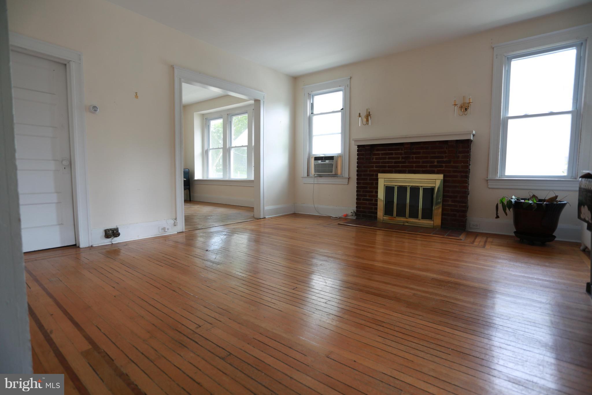 2317 Monticello Road Baltimore, MD 21216 - Photo 2 of 30 an empty room with wooden floor fireplace and windows