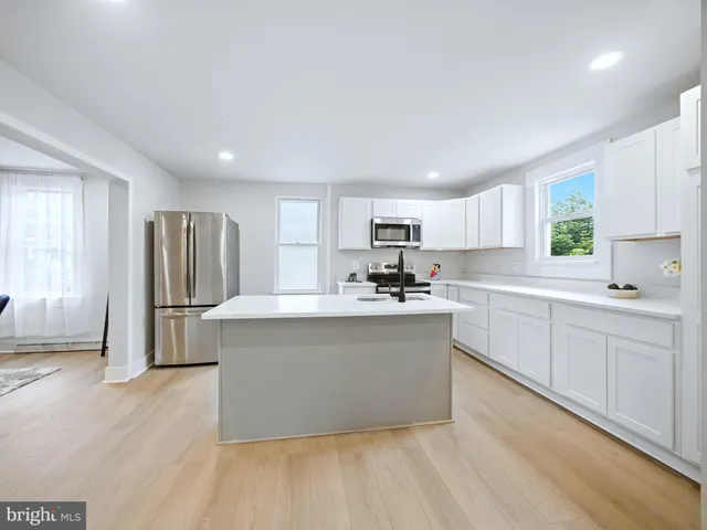 a kitchen with stainless steel appliances a sink a refrigerator and white cabinets