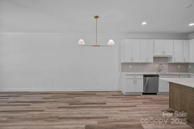 a view of a kitchen with white cabinets and wooden floor