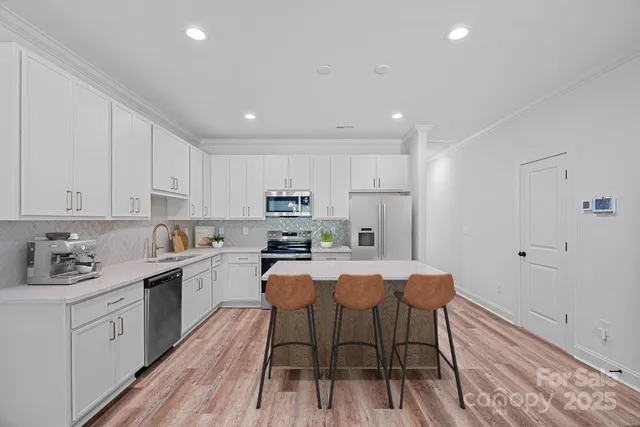 a kitchen with stainless steel appliances a white table chairs refrigerator and sink